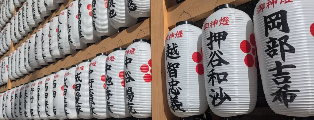 A long row of large Japanese lanterns with Japanese calligraphy in black and red lettering